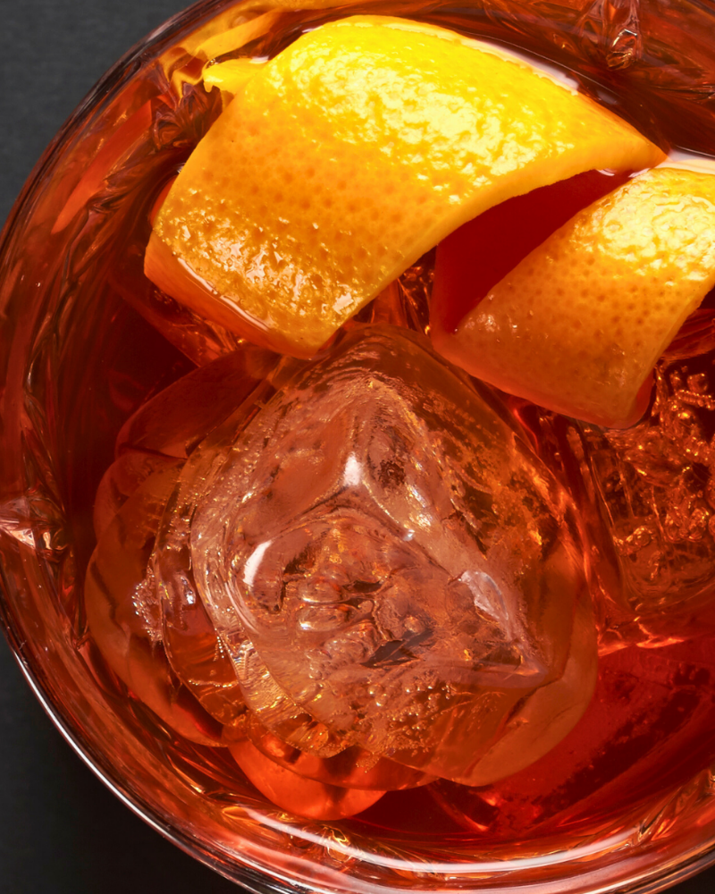Zero-proof citrus cocktail served over clear ice with fresh orange and grapefruit garnish in a minimalist glass setting.