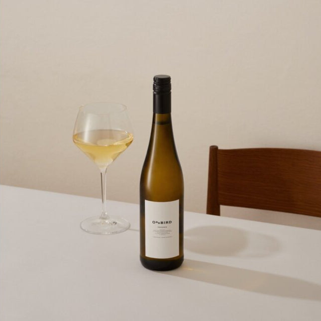Wine bottle and glass on a table with a neutral background