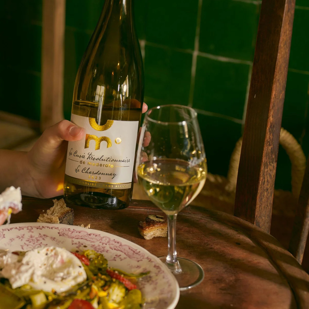 Bottle of white wine with a glass on a table with food