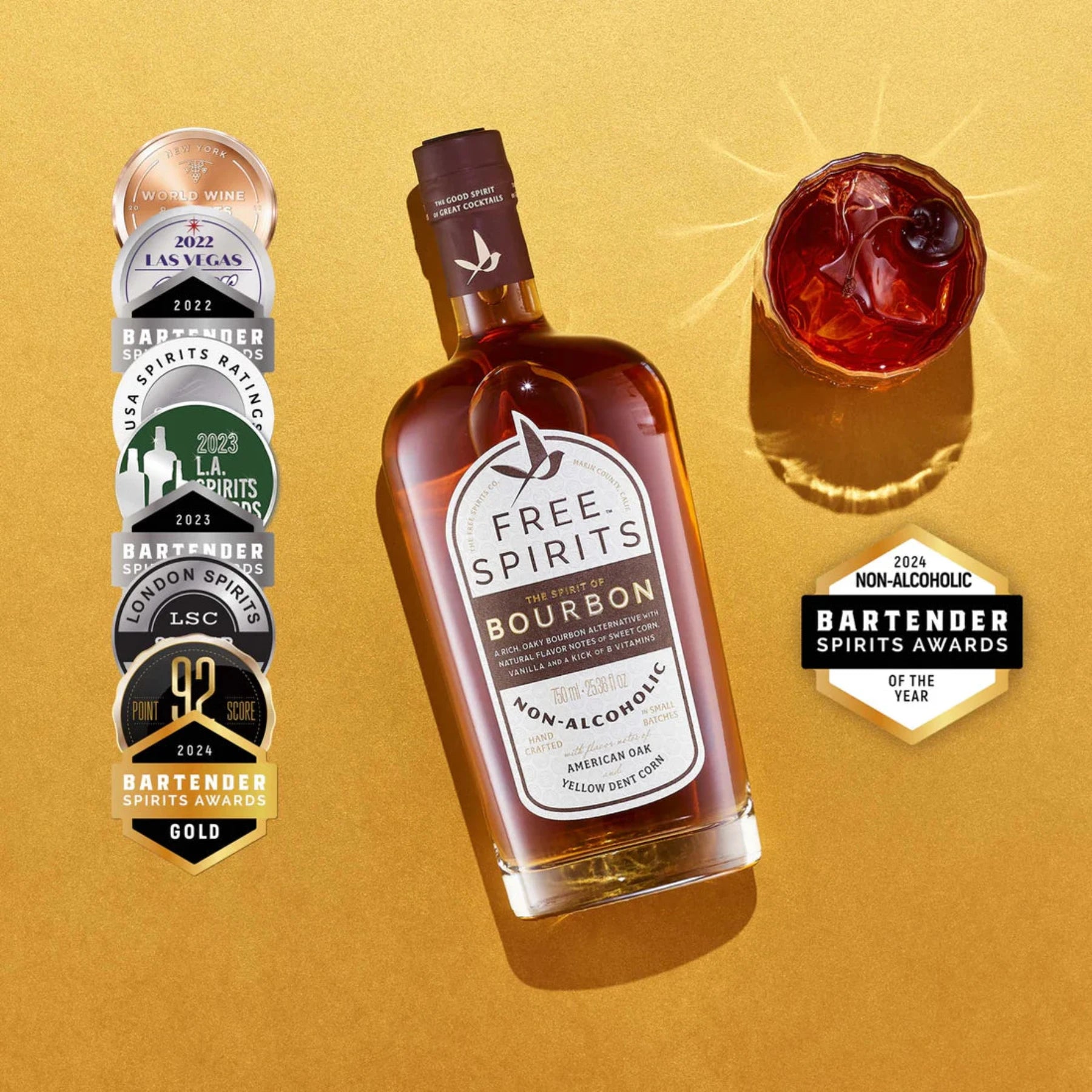 bottle of free spirits non-alcoholic-bourbon flat lay on golden surface with negroni cocktail and a stack of bartender award stickers to the left.