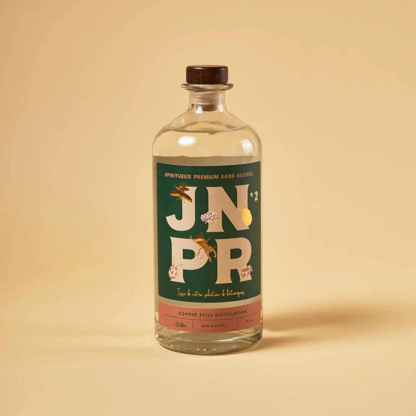 A bottle of JNPR Non-Alcoholic Gin from The Bartender Series, featuring a rich amber liquid and a stylish label with bold "JNPR" typography. The design incorporates artistic illustrations of botanicals, emphasizing its premium, handcrafted essence.