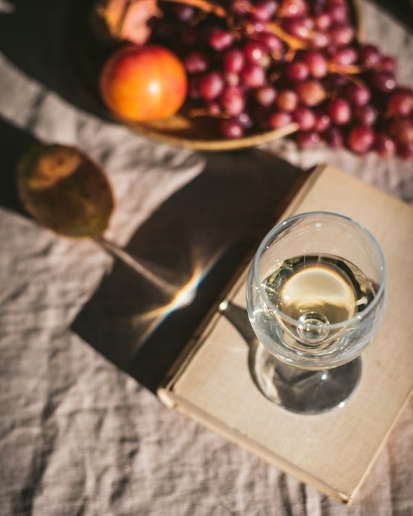 Editorial still-life photograph of a wine glass filled with non-alcoholic wine on a neutral surface, softly lit with natural light.