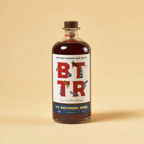 A bottle of BTR Non-Alcoholic Spirit from The Bartender Series, featuring a rich amber liquid and a stylish label with bold "BTTR" typography. The design incorporates artistic illustrations of botanicals, emphasizing its premium, handcrafted essence.