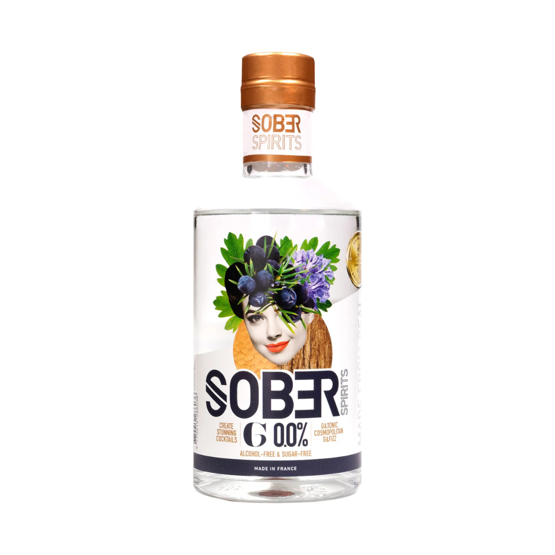 Sober Spirits G 0.0% non-alcoholic gin in a 500ml bottle with copper cap and artistic label featuring a woman’s face adorned with juniper berries, lavender, and herbs. The label highlights “Alcohol-Free & Sugar-Free” and cocktail suggestions like G&T and Cosmopolitan. Made in France.