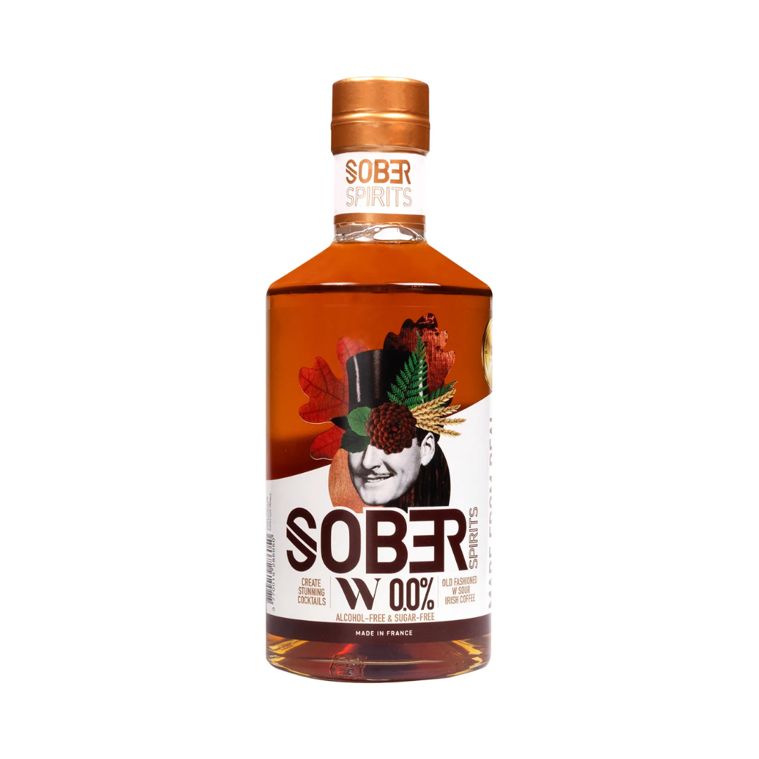 Sober Spirits W 0.0% non-alcoholic bourbon alternative in a 500ml bottle with copper cap and surreal collage-style label featuring a man in a top hat surrounded by fall leaves and grains. The label highlights "Alcohol-Free & Sugar-Free" and cocktail suggestions like Old Fashioned and Irish Coffee. Made in France.