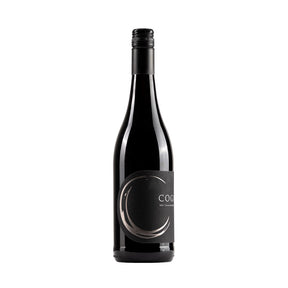 The image shows a dark wine bottle with a black label. The label has a minimalist design featuring a metallic, crescent-shaped swirl on the left side and the word "COG" in the center in simple, modern lettering. Below "COG," the text reads "RED" in smaller print, indicating that this is a red wine. The bottle has a black screw cap, giving it a sleek, contemporary appearance.