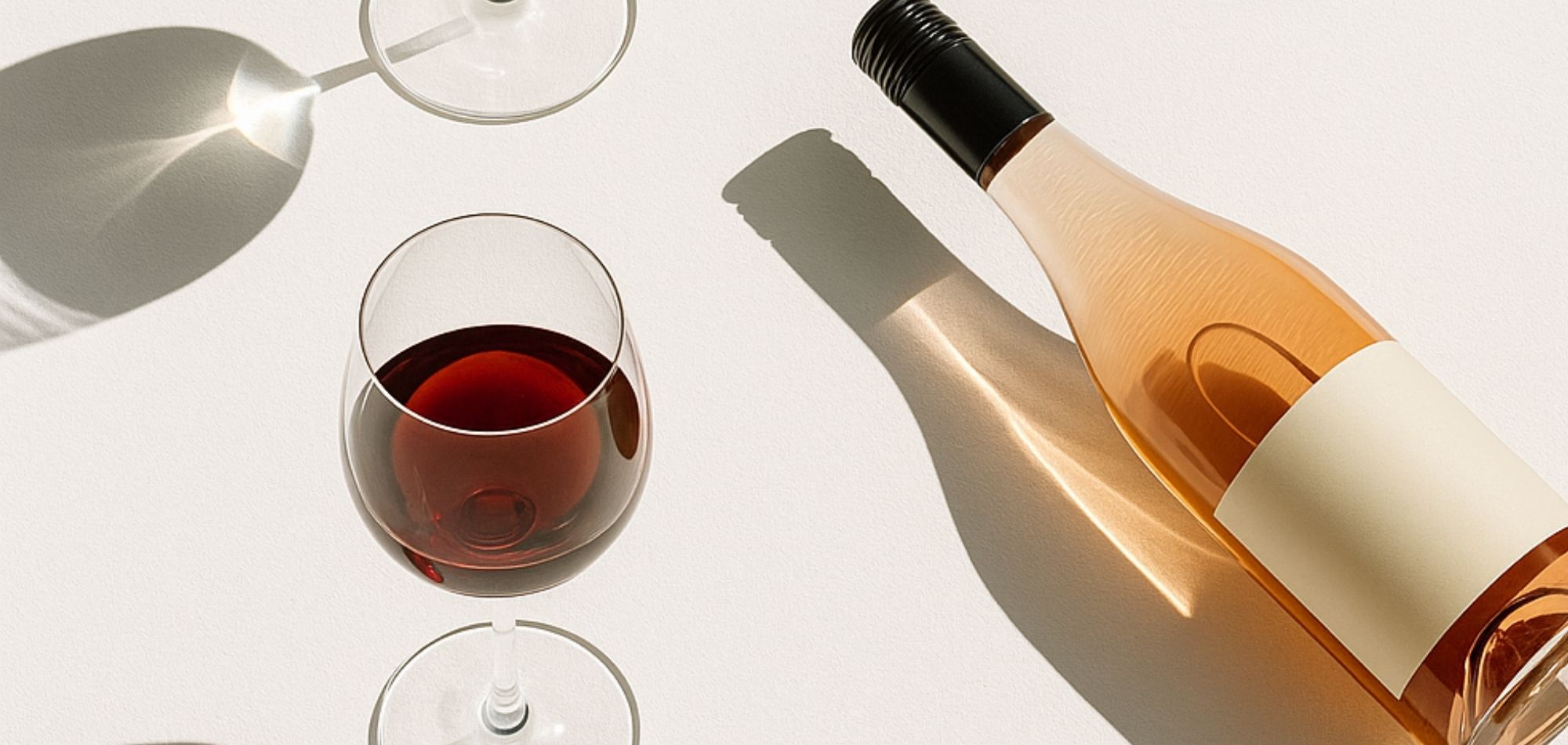 Bottle of rose wine and a glass on a white surface