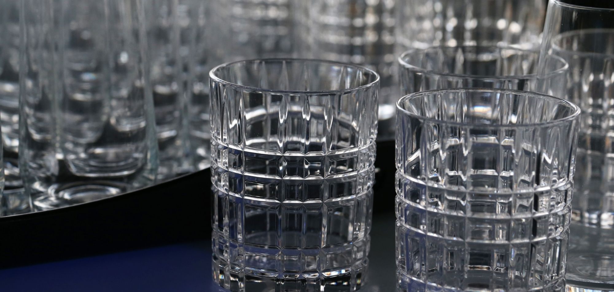 Soft, abstract glassware background with subtle light reflections, used as a hero image for non-alcoholic cocktail recipes.