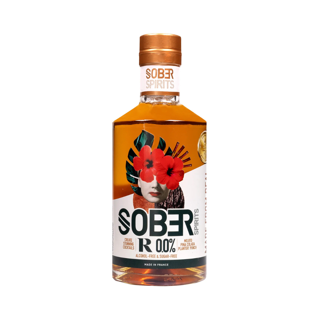 Sober Spirits R 0.0% non-alcoholic rum in a 700ml bottle with a copper cap and bold artistic label featuring a floral collage over a woman’s face. The label highlights "Alcohol-Free & Sugar-Free," and suggests use in cocktails like Mojitos and Piña Coladas. Made in France.