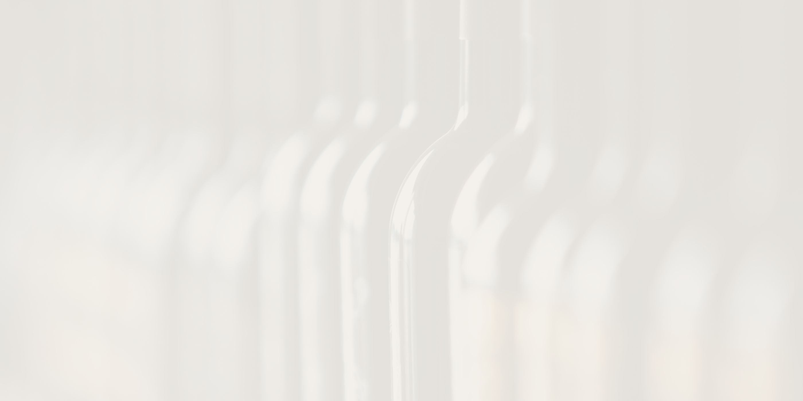 Abstract, softly blurred image of glass bottle silhouettes in light neutral tones, used as a background texture.